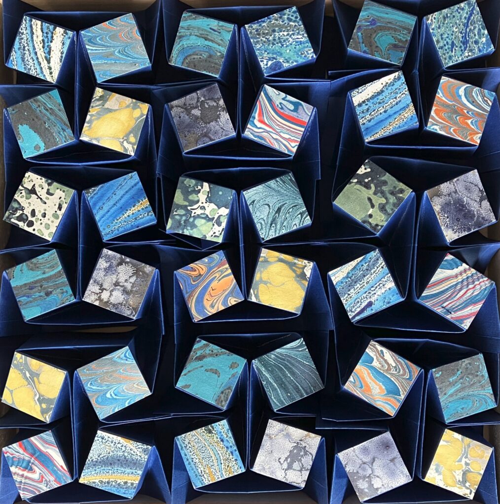 Das Objekt spielt mit klaren Strukturen und der Lebendigkeit der zugefügten Marmorpapiere.